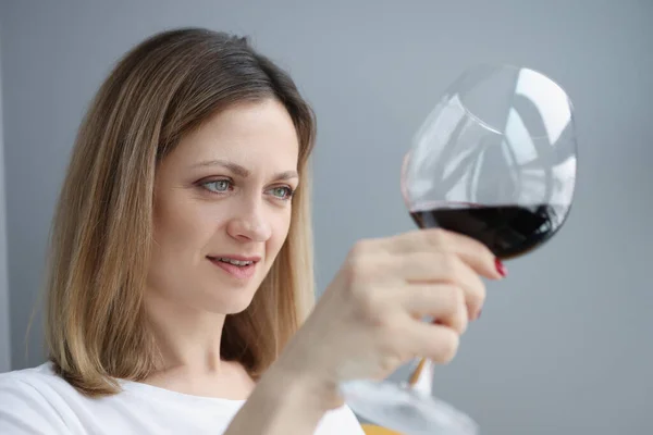 Jeune femme regardant dans le verre avec du vin rouge — Photo