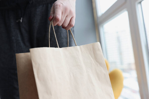 Woman hand holding paper bag at home closeup