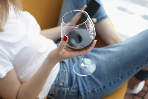 Femme tient smartphone et verre de vin dans ses mains — Photo