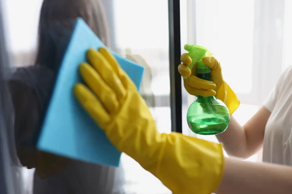 As mãos femininas em luvas amarelas lavam janelas com trapo e agente de limpeza — Fotografia de Stock