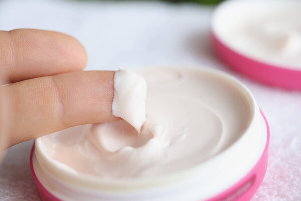White natural cosmetic cream on fingers closeup