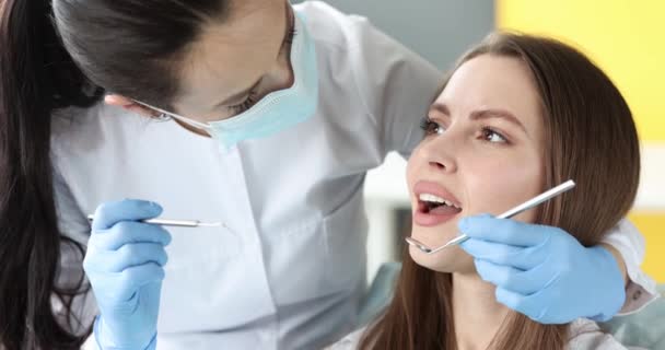 4k 영화에서 여성 환자의 치아를 검사하는 보호용 마스크를 착용 한 치과 의사 — 비디오
