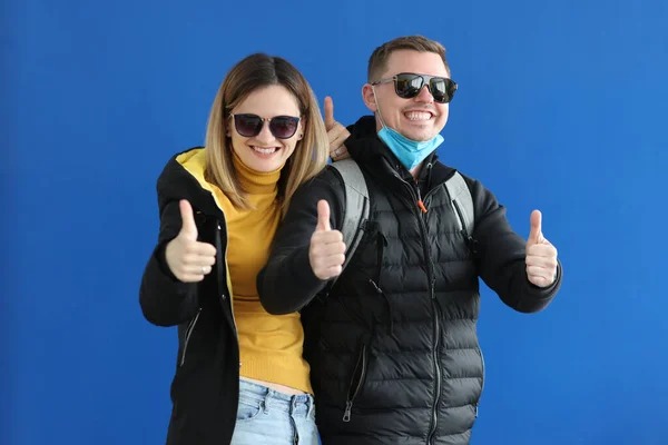 Ung man och kvinna i solglasögon och varma kläder visar tummen upp — Stockfoto