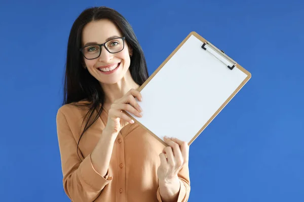 Femme avec des lunettes tenant une feuille de papier vierge dans ses mains — Photo