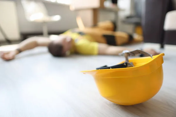 Geel veiligheidshelm ligt op de vloer in de buurt van dode werknemer concept — Stockfoto