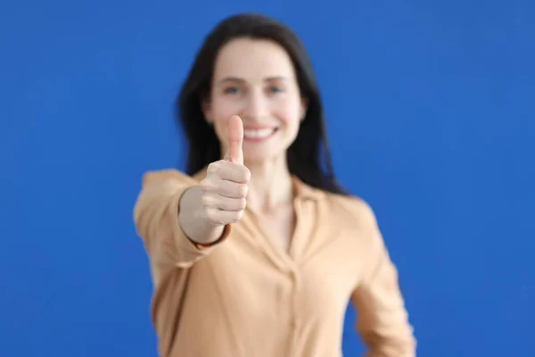 Jonge vrouw tonen duim omhoog op blauwe achtergrond closeup — Stockfoto