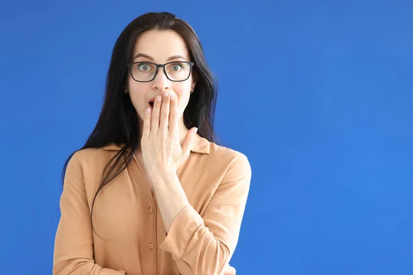 Mujer sorprendida con gafas cubre su boca con su mano —  Fotos de Stock