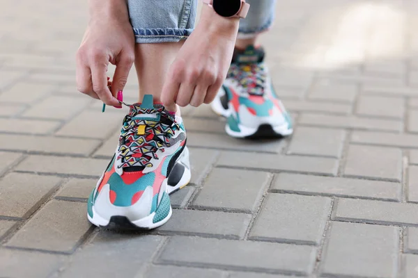 Kvinnliga hand binda snören på flerfärgade sneakers närbild — Stockfoto