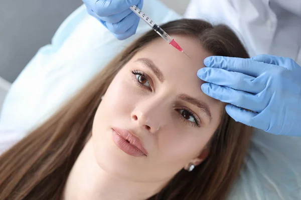 Портрет женщины, чей косметолог делает инъекцию ботулотоксина во лбу — стоковое фото