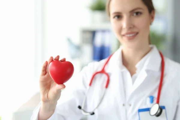 Mulher cardiologista detém pequeno coração vermelho em sua mão — Fotografia de Stock