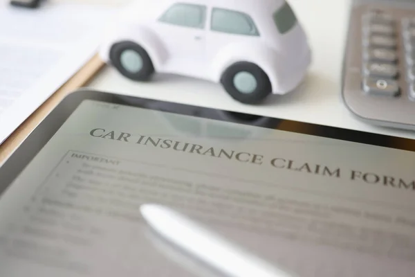 Digital tablet with car insurance form lying on table near toy car closeup — Stock Photo, Image