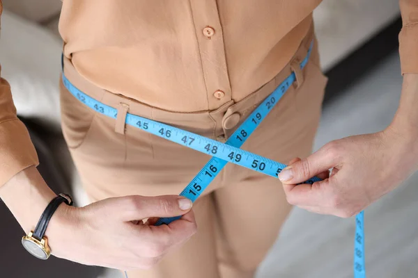 Mujer en pantalones que miden la cintura con cinta centímetro de primer plano — Foto de Stock