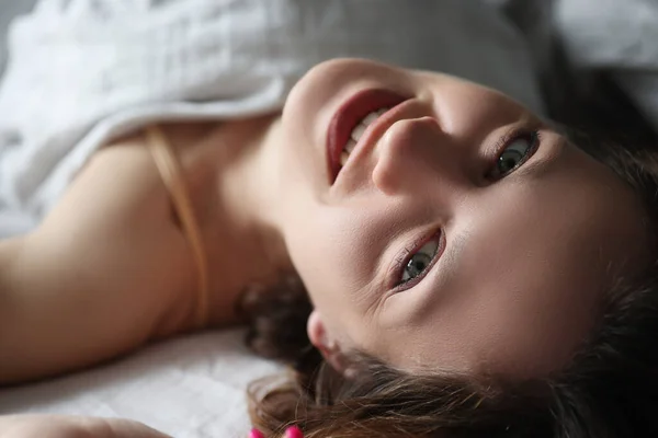 Joven mujer sonriente acostada en la cama y mirando hacia arriba —  Fotos de Stock