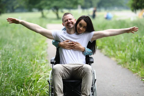 Kvinna kramar glad man i rullstol i parken — Stockfoto