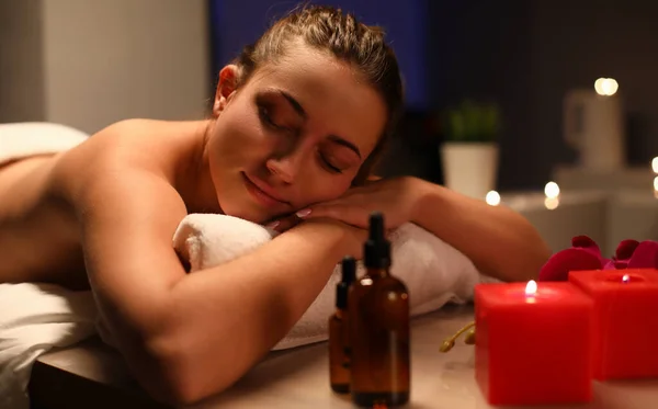 Ontspannen vrouw ligt in spa centrum in donkere kamer bij kaarslicht — Stockfoto