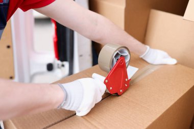 Karton kutu paketleyen bir adam, yakın çekim bandı kullanıyor.