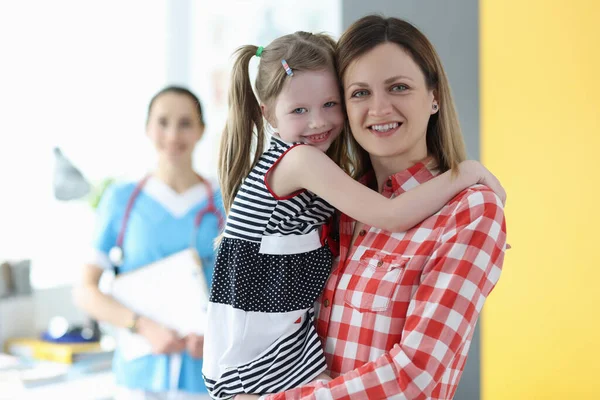 Anya kislányt tart a karjaiban az orvosi vizsgálaton. — Stock Fotó