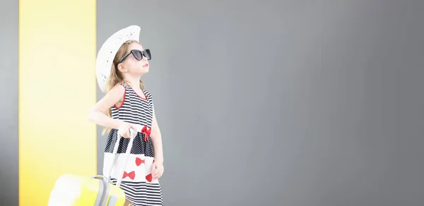 Niña en gafas de sol y sombrero caminando con maleta en la mano — Foto de Stock