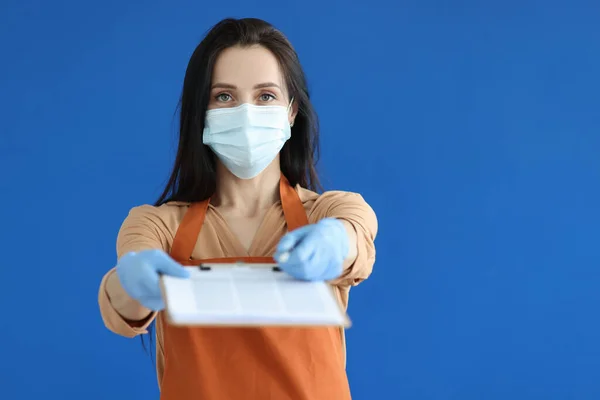 Vrouw verkoper in beschermende masker en handschoenen geven klembord met documenten voor ondertekening — Stockfoto