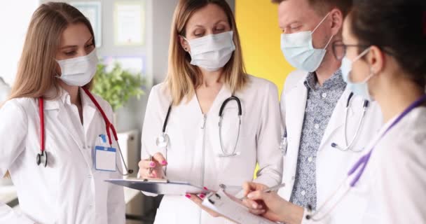 Группа врачей в масках, общающихся в клинике 4К фильм — стоковое видео