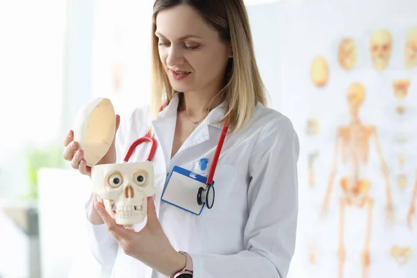 Kobieta lekarz w białym płaszczu trzyma manekina ludzkiej czaszki — Zdjęcie stockowe