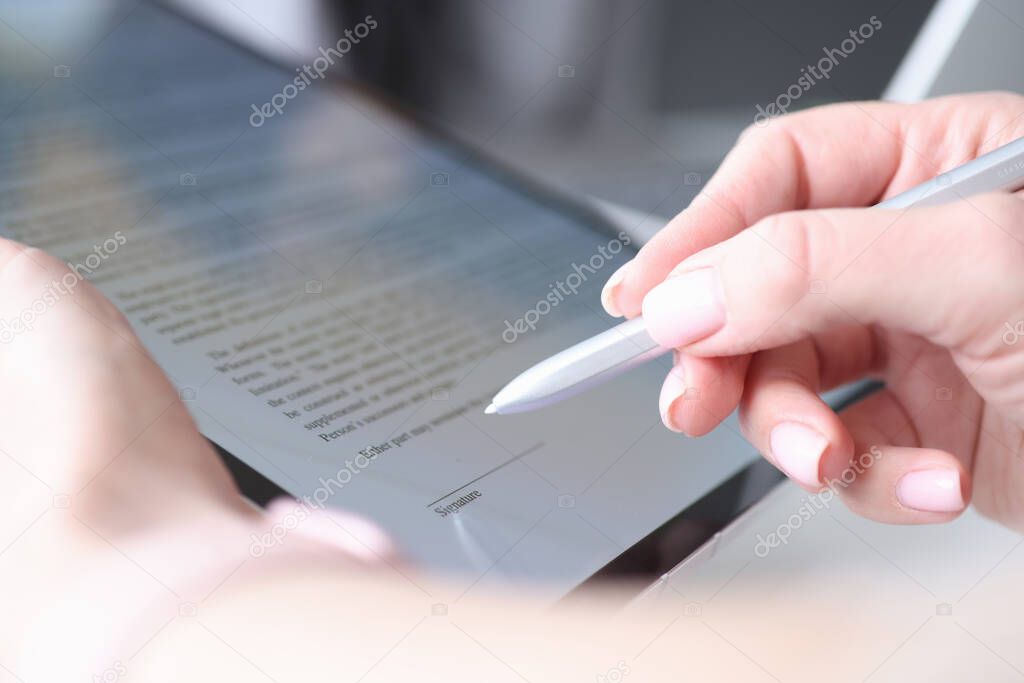Woman hand holds stylus and puts an electronic signature in contract on tablet