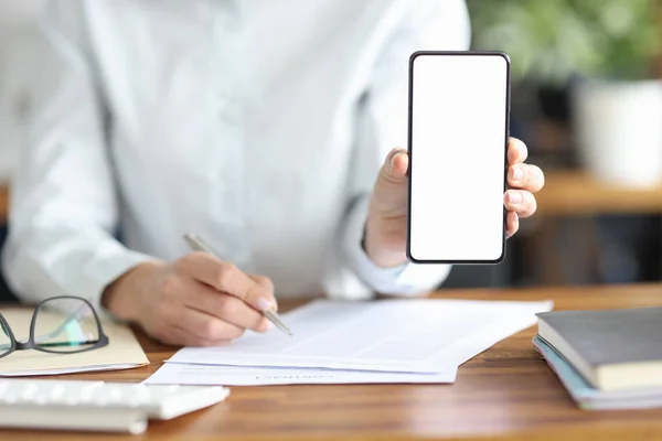 İş kadını sözleşmeyi imzaladı ve elinde beyaz ekranlı akıllı telefon tutuyor — Stok fotoğraf
