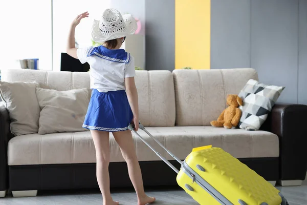 Little girl stands with her back with yellow suitcase — Stock Photo, Image