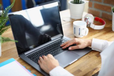 Ofisteki çalışma masasında dizüstü bilgisayarda çalışan kadın eller.