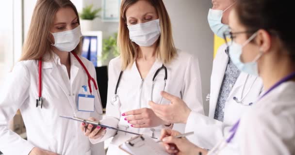 Grupp av läkare som bär skyddsmasker kommunicerar på klinik 4k film — Stockvideo