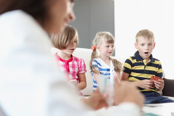 Kinderen zitten op de bank en spelen bordspelletjes met hun ouders — Stockfoto