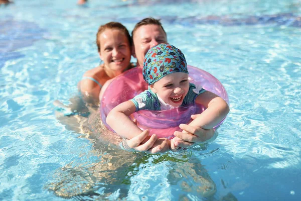 Kislány kör és a szülők úszás medencében — Stock Fotó
