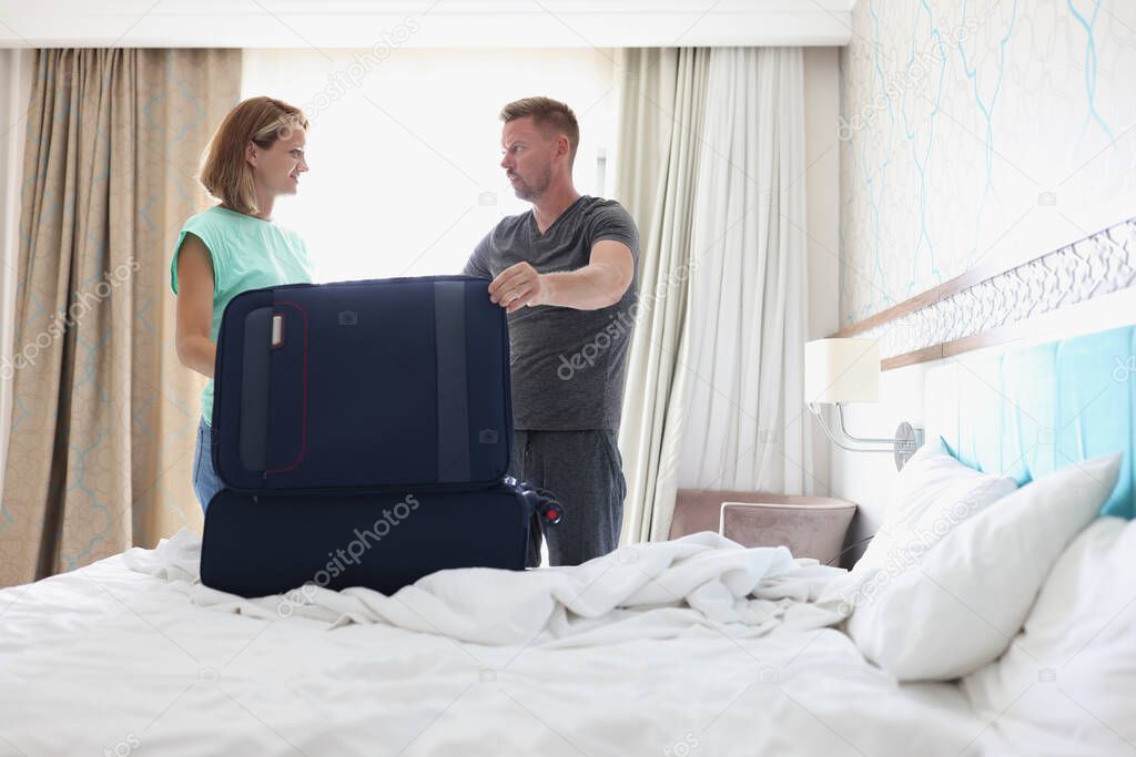Young man and woman packing in suitcase in bedroom