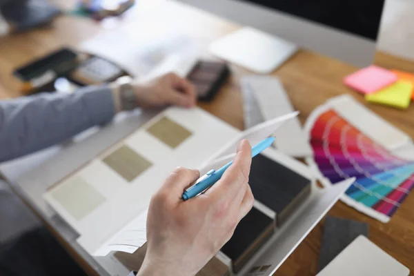 Man designer está folheando através de catálogo com amostras de close-up placa laminada — Fotografia de Stock