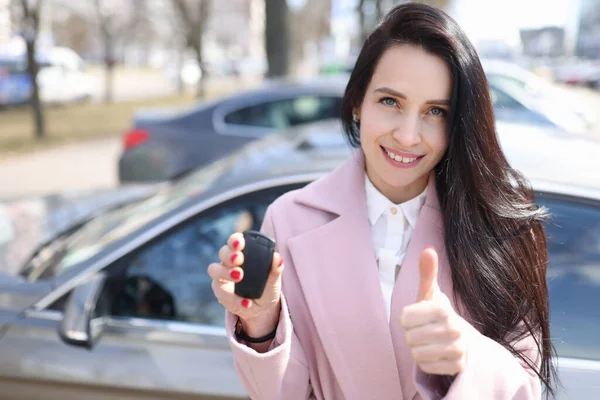 Jonge vrouw met autosleutels en tonen duim omhoog — Stockfoto