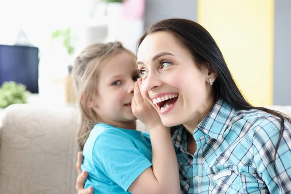 Liten flicka viskar hemlighet till mamma öra hemma — Stockfoto