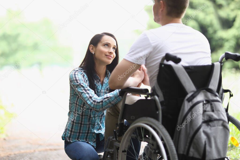 Woman looks with loving gaze at man in wheelchair