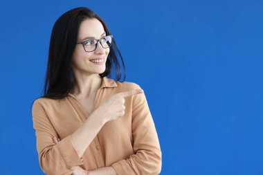 Gözlüklü, güzel, gülümseyen kadın reklamlara işaret ediyor.