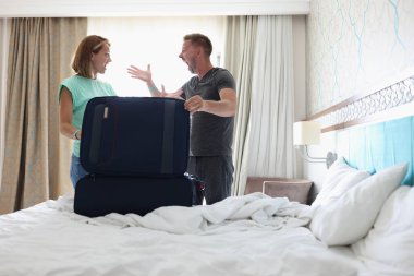 Kadın ve erkek yatak odasında kavga ediyor. Yatakta bavul var.