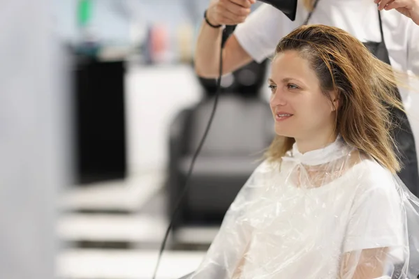 Мастер парикмахерская сушит волосы с феном, чтобы аклиент в салоне красоты — стоковое фото