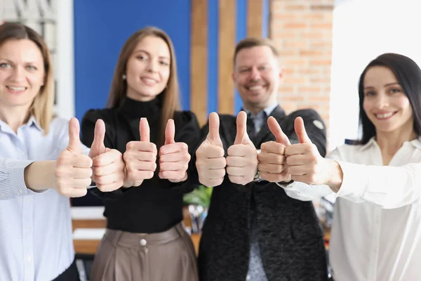 Pessoas de negócios sorridentes mostram polegares para cima gesto stand no escritório — Fotografia de Stock