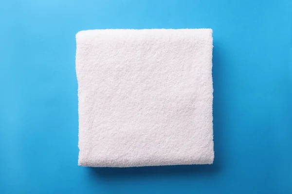 Белое махровое полотенце сложено на синем фоне — стоковое фото