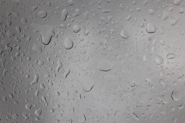 Dešťové kapky na sklo proti šedé obloze detailní up — Stock fotografie
