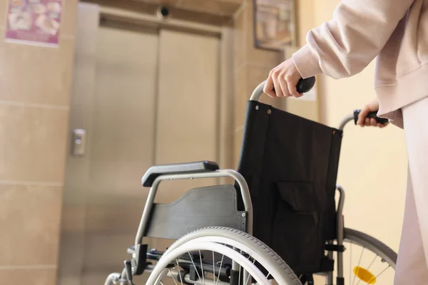 Woman rolls wheelchair to the elevator to meet disabled person