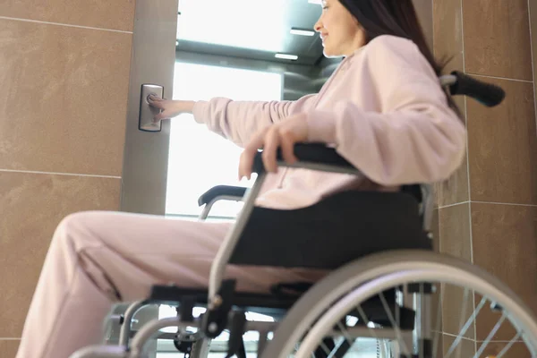 Усміхнена жінка в інвалідному візку натискає кнопку ліфта — стокове фото