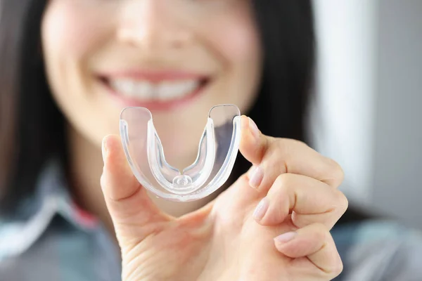 Uśmiechnięta kobieta trzyma w ręku przezroczysty plastikowy ochraniacz na zęby — Zdjęcie stockowe