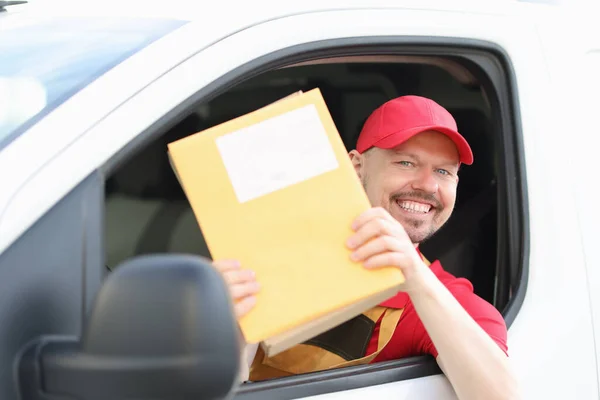 Sorrindo mensageiro masculino motorista mantém correio em suas mãos — Fotografia de Stock