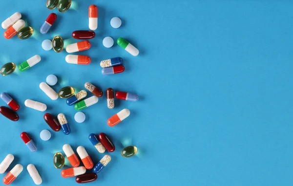 Las píldoras médicas multicolores se encuentran en el fondo azul — Foto de Stock