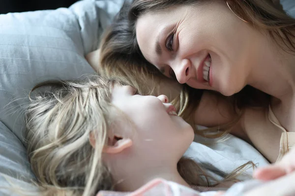 Mamma e figlia ridono e si guardano mentre si trovano a letto — Foto Stock