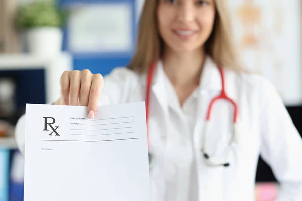 Female doctor is holding blank form of medical prescription